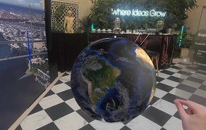A large globe on a pedestal inside a showroom or exhibit, with a black-and-white checkered floor and the slogan 'Where ideas grow' in the background.