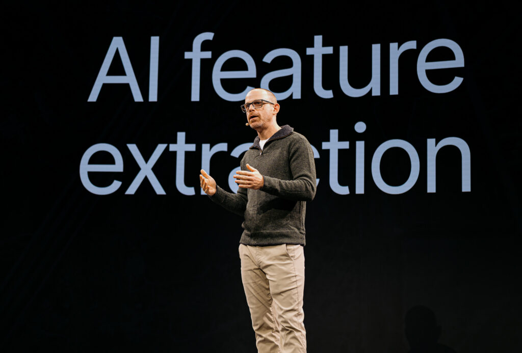 Patrick Cozzi, founder of Cesium and Chief Platform Officer at Bentley Systems giving a presentation about "AI feature extraction," highlighting the technology focus of the event sessions.