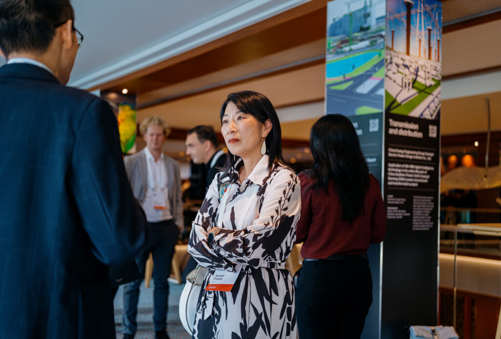 An attendee networking during a break at the Year in Infrastructure event, with a project showcase in the background.