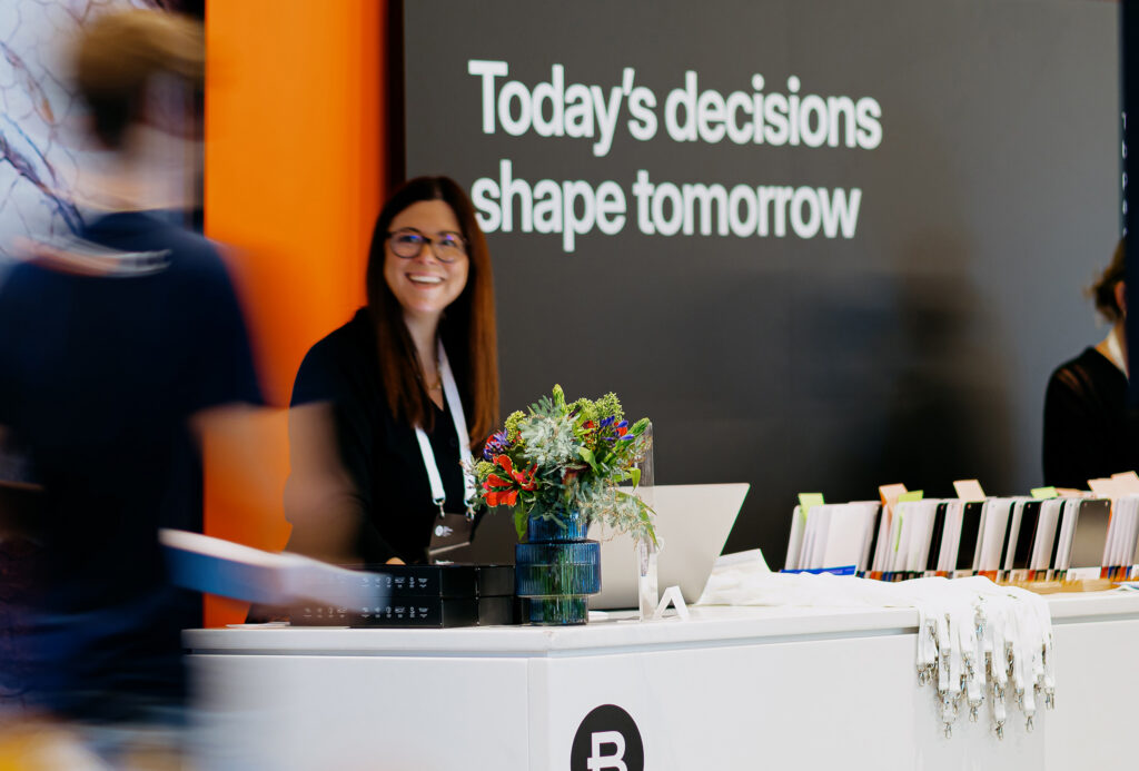 A smiling staff member at the Year in Infrastructure event registration desk, ready to welcome attendees.