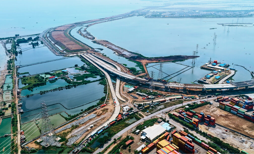 An aerial view of the Semarang-Demak Toll Road construction, showing the highway and sea wall being built along a coastline, a finalist project by PT PP-WIKA KSO.