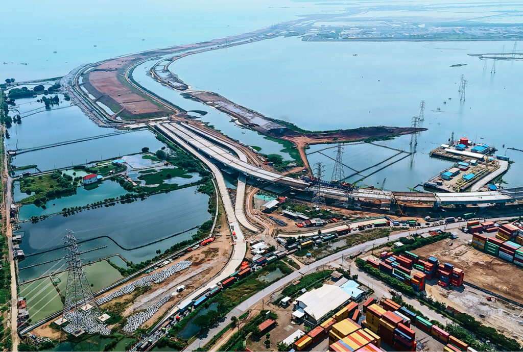 An aerial view of the Semarang-Demak Toll Road construction, showing the highway and sea wall being built along a coastline, a finalist project by PT PP-WIKA KSO.