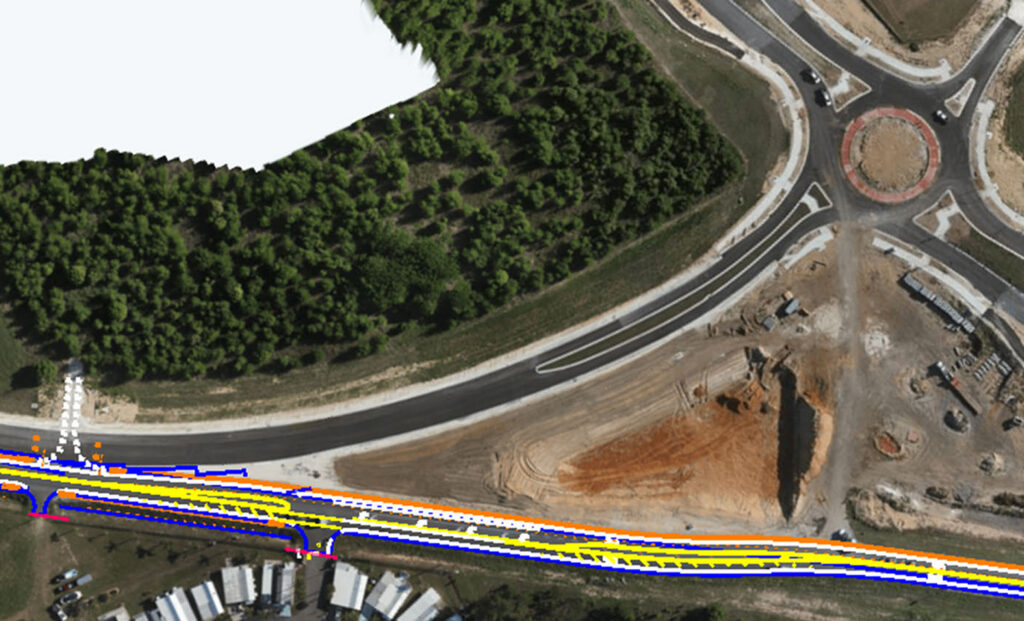 Aerial view of a road construction site with a circular roundabout, paved lanes, and surrounding forested area.