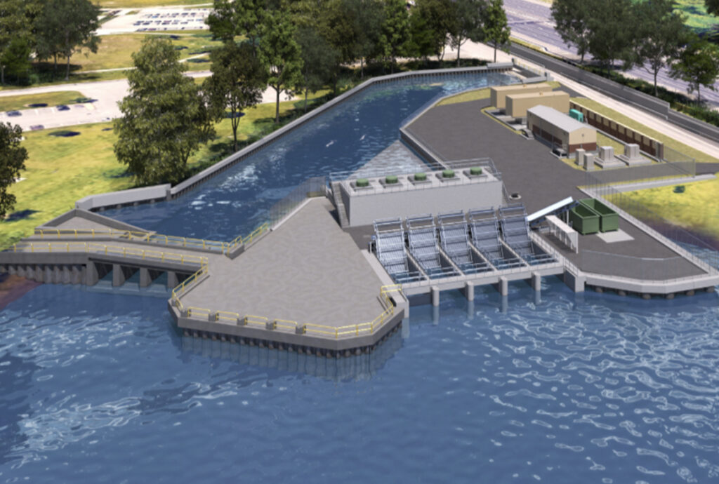 Aerial view of a water treatment or dam facility with a long concrete platform extending into a blue body of water and trees nearby.