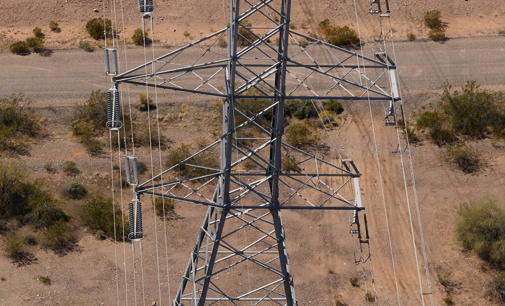 An aerial, top-down photograph of a steel lattice transmission tower in a desert environment, a finalist project by Arizona Public Service.