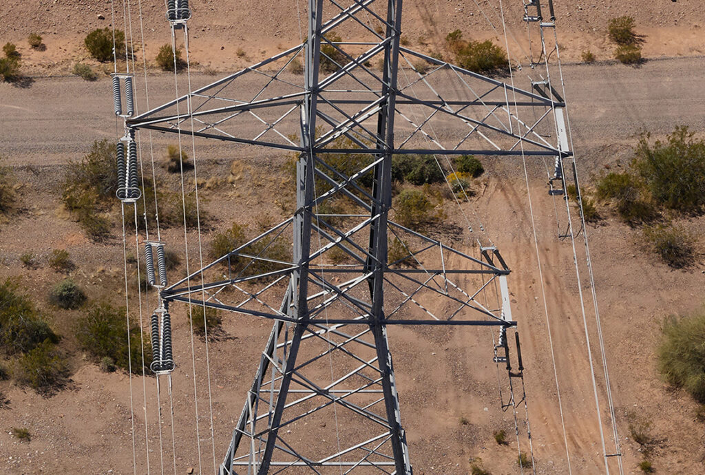 An aerial, top-down photograph of a steel lattice transmission tower in a desert environment, a finalist project by Arizona Public Service.