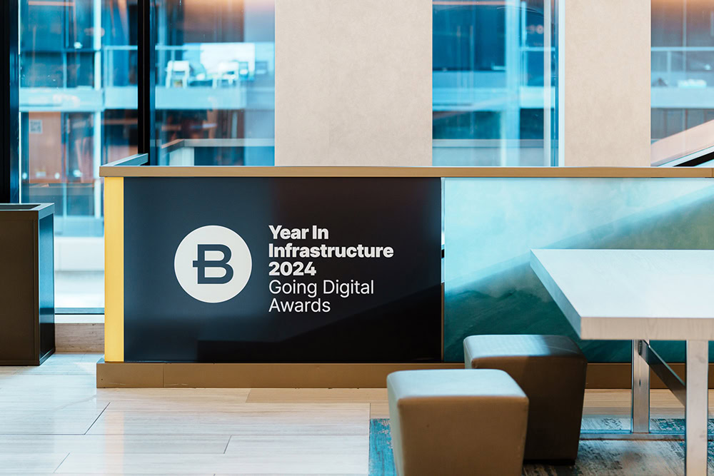 Lobby area with a sign that reads "Year In Infrastructure 2024 Going Digital Awards" next to modern furniture and large windows.