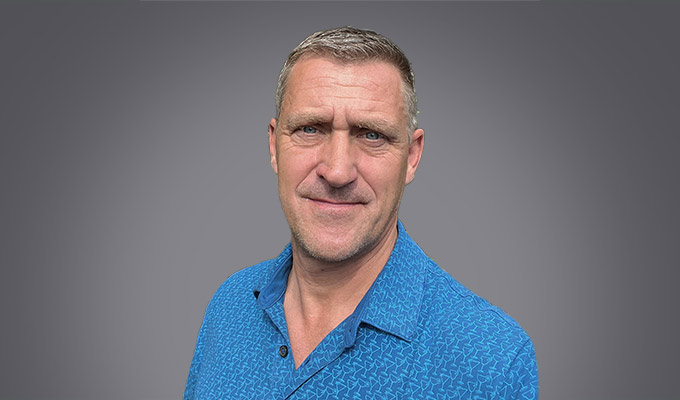 Holger Kessler, a middle-aged man with short gray hair, poses in a blue patterned shirt against a plain gray background.