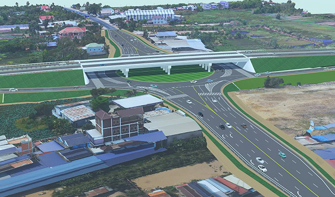 Aerial view of the Phnom Penh Expressway interchange in Bavet, featuring overpasses, multiple roads with vehicles in motion, and surrounding buildings and fields.
