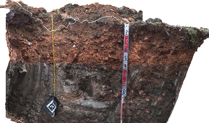 A vertical soil profile with distinct layers, a measuring tape showing depth, and a plumb line for reference provides valuable subsurface insight.