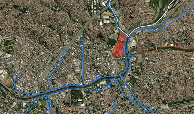Aerial satellite view of a dense urban area with roads and rivers highlighted in blue and red, illustrating how digitalization is shaping infrastructure; a section near the center-right is shaded red.