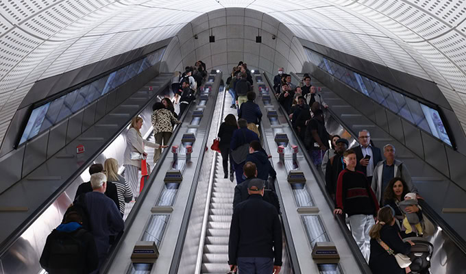 People ride up and down a set of parallel escalators in a modern, well-lit station on the Elizabeth Line, part of London’s innovative Crossrail network.
