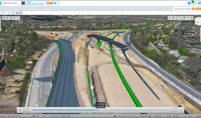 A digital 3D model of a highway construction site, highlighting the M80 Ring Road completion with multiple roads, overpasses, and an adjacent landscape featuring trees and buildings.