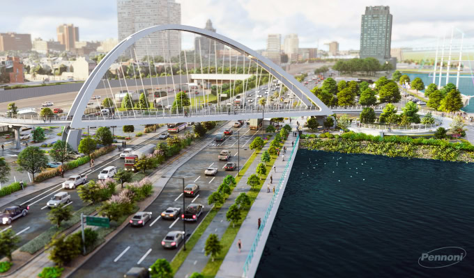 A modern arched pedestrian bridge spans over a busy multi-lane road next to a river at Penn’s Landing, with city buildings, trees, and green spaces on both sides—a centerpiece of the I-95 CAP project.