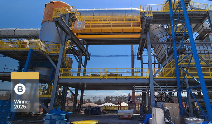 Large industrial facility with metal structures, pipes, and platforms under a clear blue sky, showcasing 500kV power transmission. A "Winner 2025" badge appears in the lower left corner.
