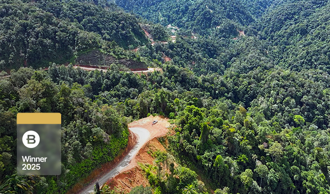 A winding road cuts through dense green forest in a mountainous area, where China Southern Power Grid uses GIS+BIM digital intelligence. A "Winner 2025" badge is displayed in the lower left corner.